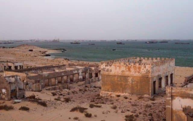 أطلال مباني الكويرة المهجورة على شبه جزيرة الرأس الأبيض، وفي الخلفية ميناء نواذيبو
